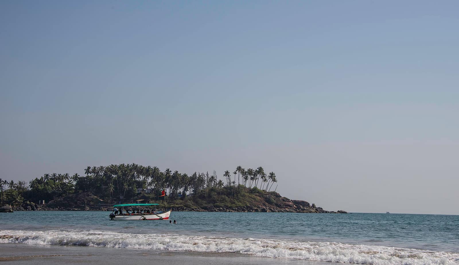 Palolem beach with palm trees and a boat in South Goa, Goa holiday tour package